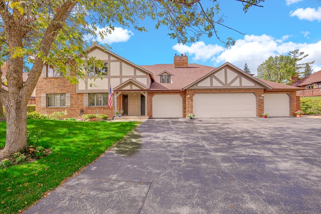 english style home featuring a front lawn and a garage