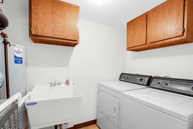 laundry area featuring water heater, sink, independent washer and dryer, and cabinets