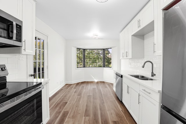 kitchen with appliances with stainless steel finishes, decorative backsplash, sink, and white cabinets