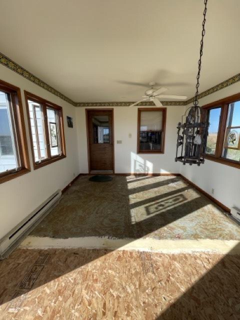 17580 1200 E St, Wyanet, IL 61379 - unfurnished living room with a baseboard heating unit, healthy amount of natural light, ceiling fan, and baseboards