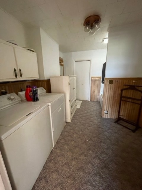 clothes washing area featuring wooden walls, washing machine and clothes dryer, cabinets, and carpet flooring