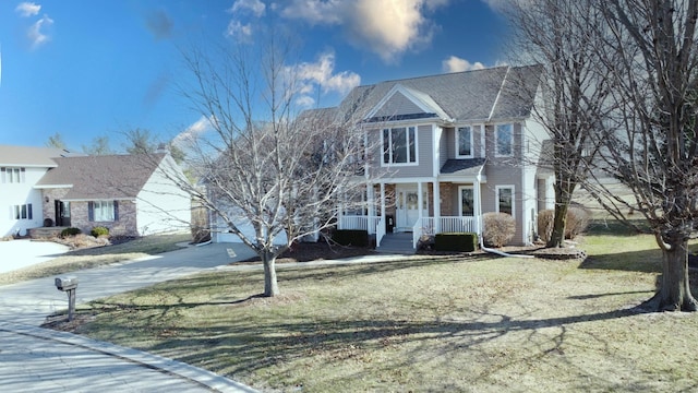 view of front of property with a porch, concrete driveway, and a front yard