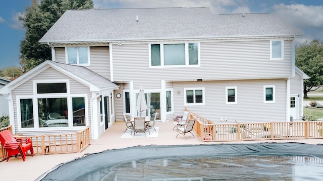 rear view of house with a fenced in pool, a patio area, and a shingled roof