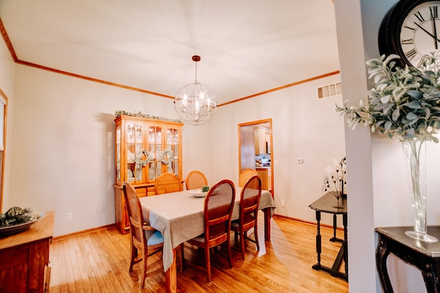 dining space with crown molding, light hardwood / wood-style flooring, and a notable chandelier