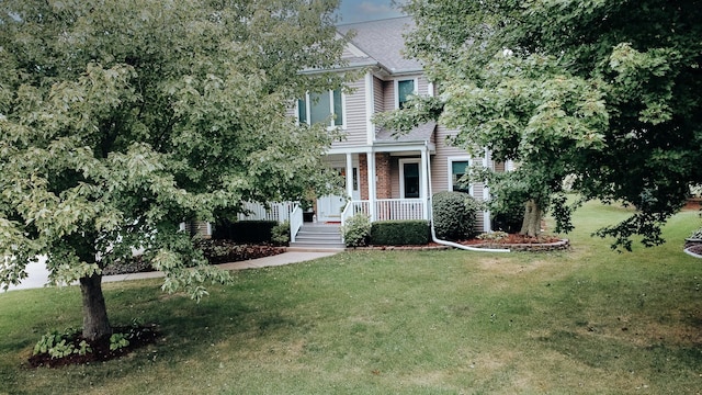 view of front of home featuring covered porch, a shingled roof, and a front lawn