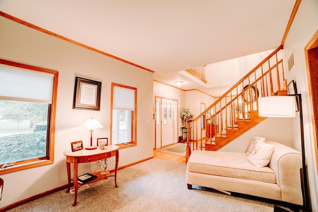 carpeted living area with stairway, visible vents, baseboards, and ornamental molding