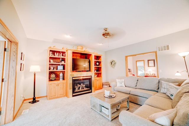 living room with visible vents, baseboards, carpet, and a glass covered fireplace