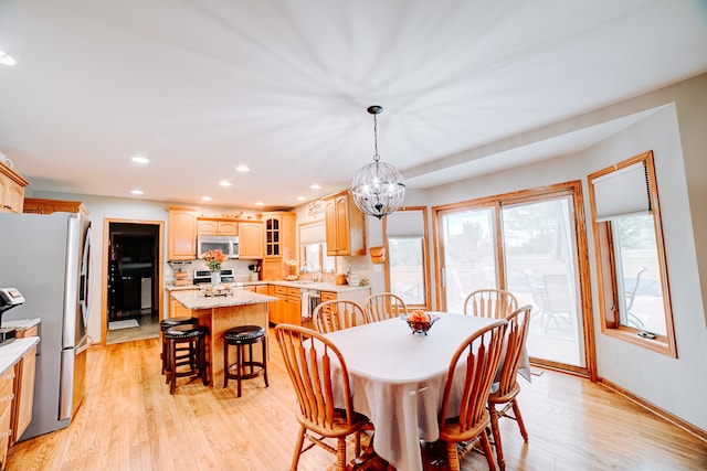 dining space featuring sink, light hardwood / wood-style flooring, and a notable chandelier