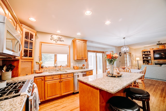 kitchen with white appliances, sink, a kitchen bar, a center island, and light hardwood / wood-style flooring