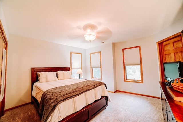 bedroom with visible vents, baseboards, light carpet, and a ceiling fan