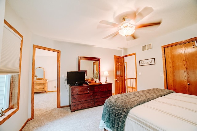 bedroom with visible vents, ceiling fan, baseboards, light carpet, and a closet