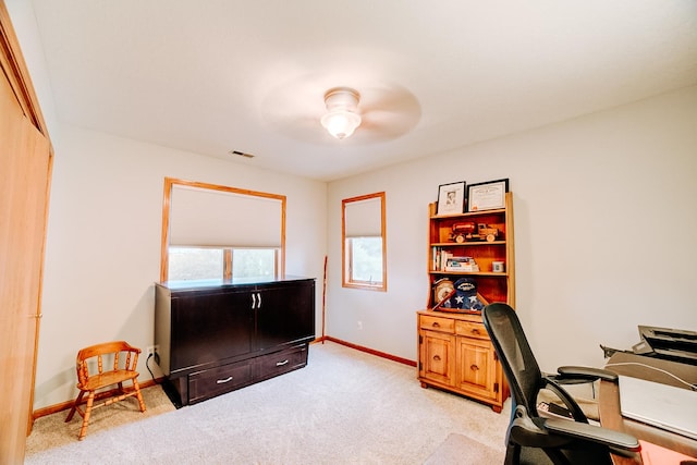 office space with visible vents, light colored carpet, a ceiling fan, and baseboards