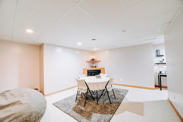 carpeted dining room with a paneled ceiling