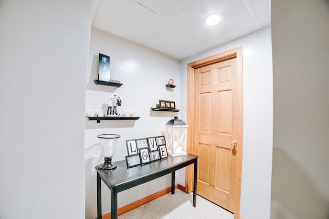 interior space featuring a paneled ceiling, baseboards, and carpet floors