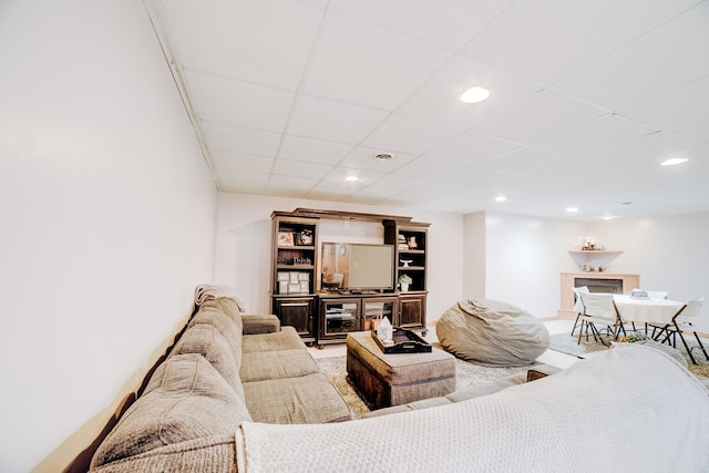living area with recessed lighting, a paneled ceiling, and a fireplace