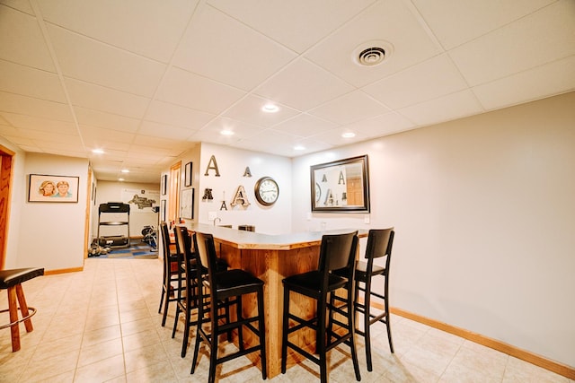dining room with a paneled ceiling, visible vents, wet bar, and baseboards