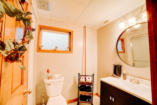 bathroom with visible vents, toilet, baseboards, a paneled ceiling, and vanity