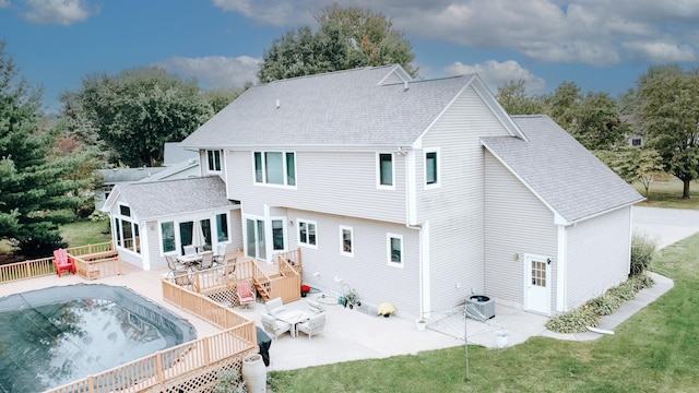 back of property featuring roof with shingles, a wooden deck, central air condition unit, a patio area, and a lawn