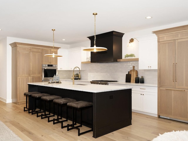 kitchen featuring white cabinets, decorative light fixtures, stainless steel appliances, tasteful backsplash, and a kitchen island with sink