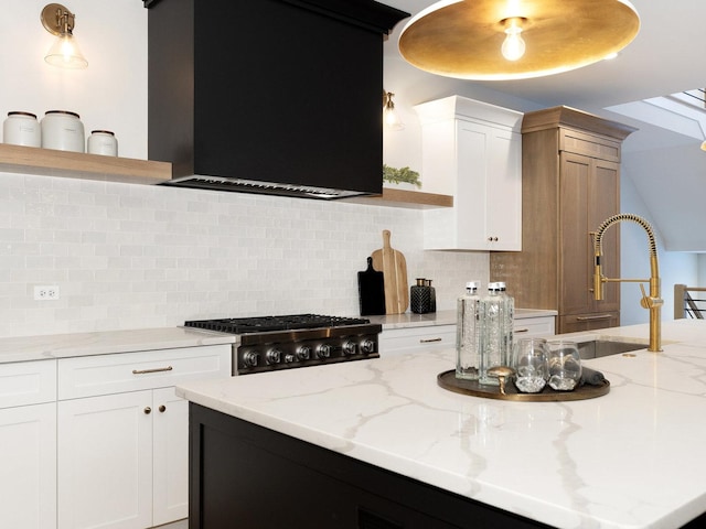 kitchen featuring backsplash, extractor fan, sink, light stone countertops, and white cabinets