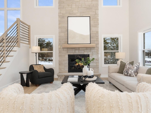 living room with a fireplace, a wealth of natural light, a high ceiling, and light hardwood / wood-style flooring