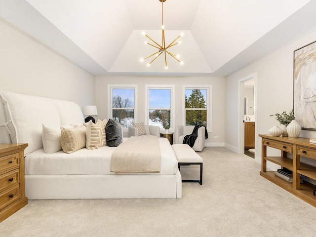 bedroom featuring connected bathroom, light carpet, a raised ceiling, and a chandelier