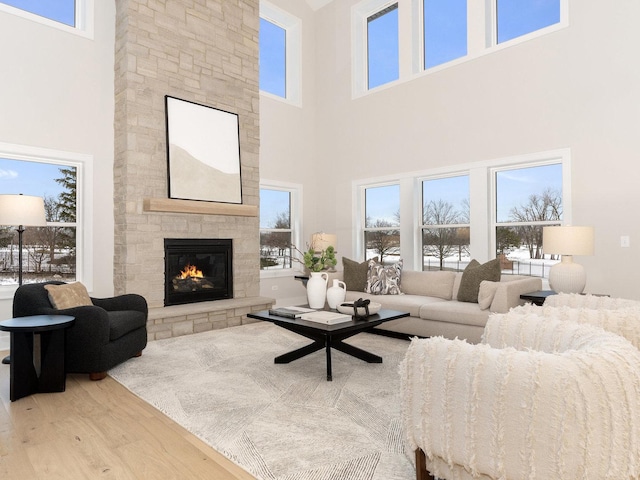 living room with hardwood / wood-style flooring, a wealth of natural light, a fireplace, and a high ceiling