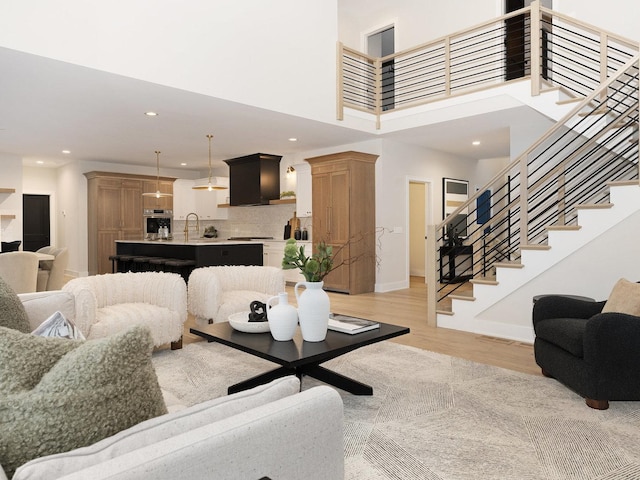 living room featuring a high ceiling, light hardwood / wood-style flooring, and sink