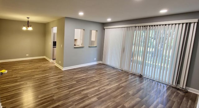 unfurnished room with an inviting chandelier and dark hardwood / wood-style flooring