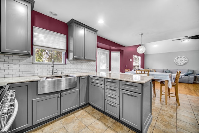 kitchen with ceiling fan, pendant lighting, sink, kitchen peninsula, and gray cabinetry