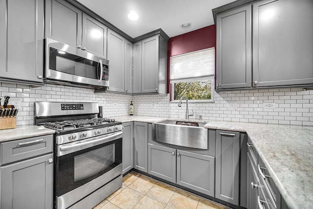 kitchen featuring appliances with stainless steel finishes, gray cabinetry, backsplash, and sink