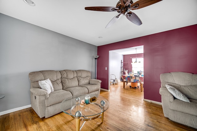 living room with ceiling fan with notable chandelier and hardwood / wood-style flooring