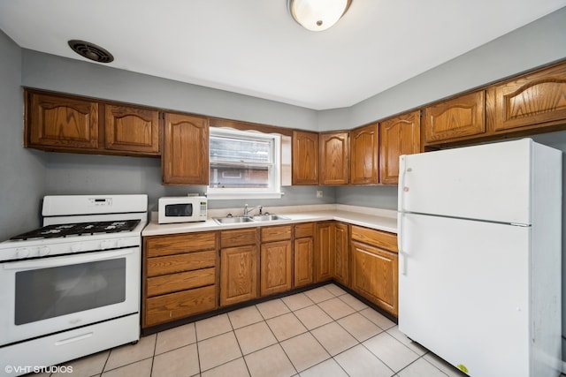 kitchen with light tile patterned floors, sink, and white appliances