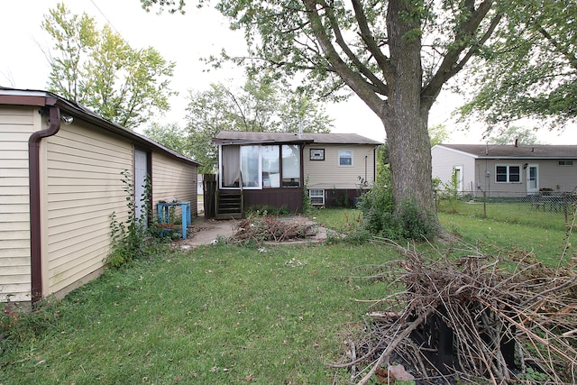 back of property with a sunroom and a yard