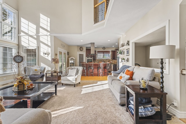 carpeted living room featuring ceiling fan, a wealth of natural light, and a high ceiling