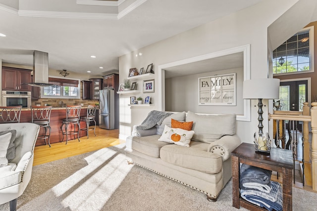 living room with light wood-type flooring, sink, and ornamental molding