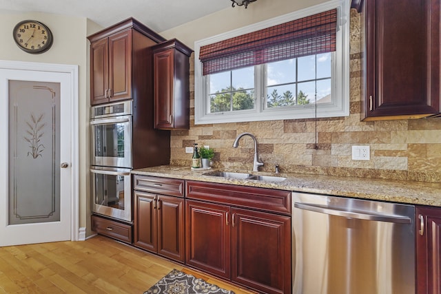 kitchen featuring light hardwood / wood-style flooring, sink, tasteful backsplash, light stone countertops, and appliances with stainless steel finishes