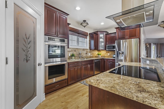 kitchen with sink, appliances with stainless steel finishes, tasteful backsplash, light stone countertops, and light hardwood / wood-style flooring