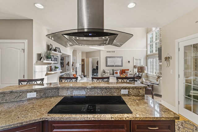 kitchen featuring light stone counters, black electric stovetop, and island range hood