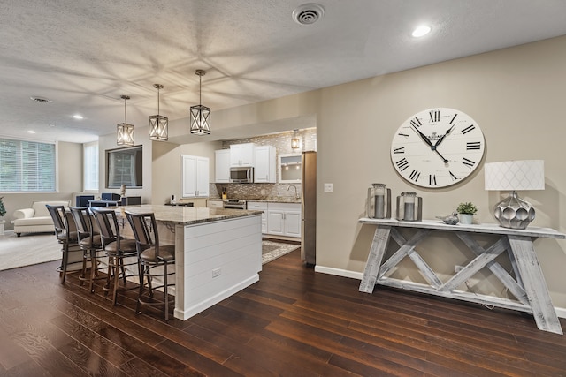 kitchen featuring white cabinets, light stone countertops, pendant lighting, and dark hardwood / wood-style flooring