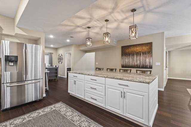 kitchen with white cabinetry, stainless steel fridge with ice dispenser, dark hardwood / wood-style flooring, light stone countertops, and hanging light fixtures