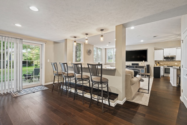 living room with dark wood-type flooring, plenty of natural light, and a textured ceiling