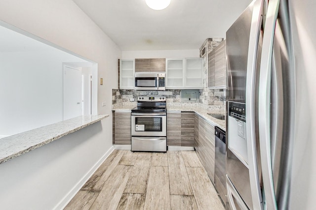 kitchen with stainless steel appliances, light stone countertops, and backsplash