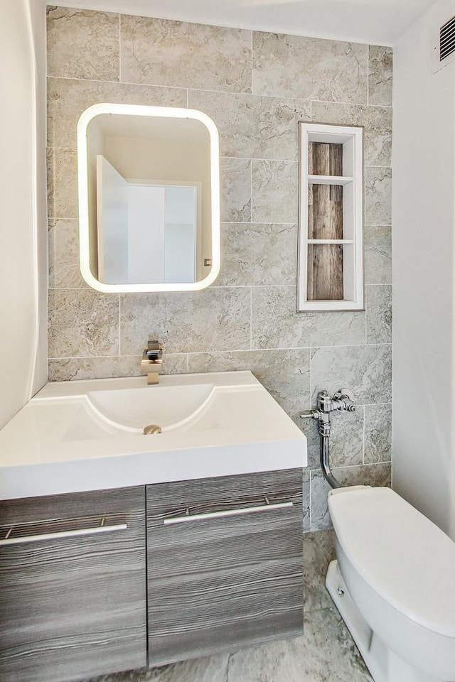 bathroom with tile walls, toilet, backsplash, and vanity