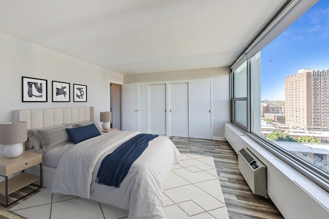 bedroom featuring light wood-type flooring, a closet, and an AC wall unit