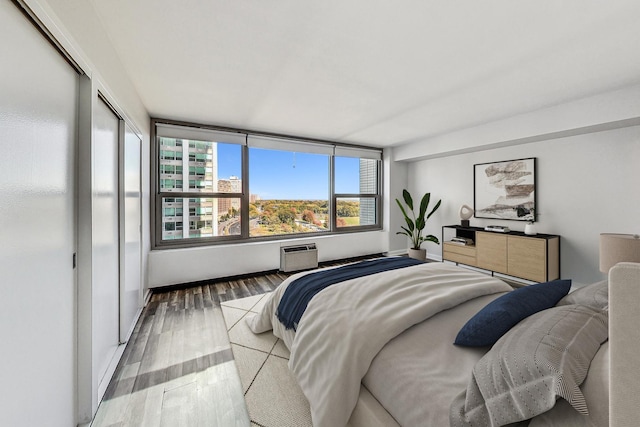 bedroom with an AC wall unit and hardwood / wood-style floors