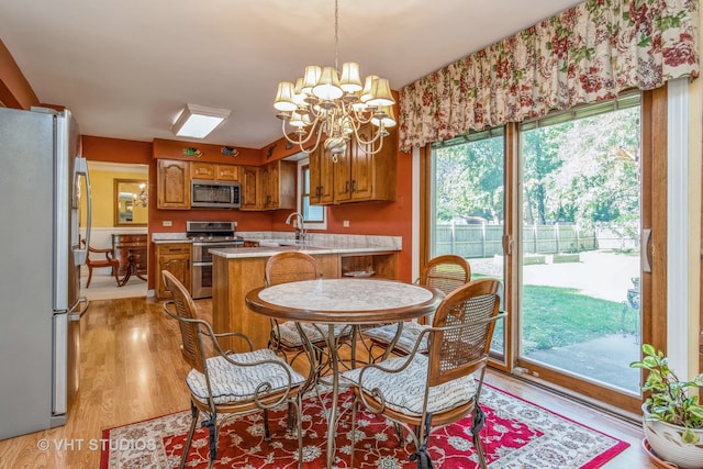 dining area featuring light wood-type flooring, a chandelier, a wealth of natural light, and sink