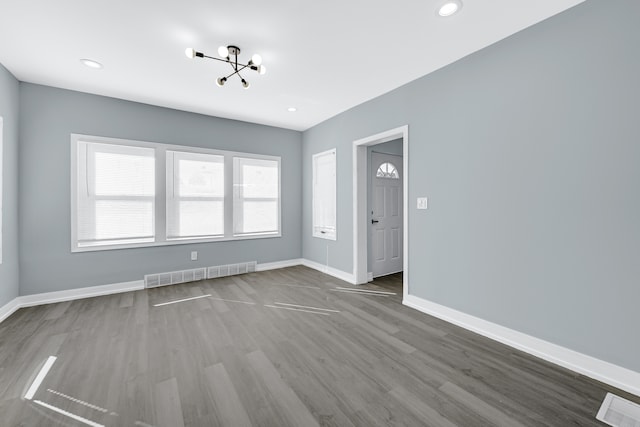 empty room with hardwood / wood-style flooring and a notable chandelier