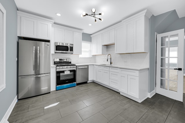 kitchen featuring sink, tasteful backsplash, a chandelier, white cabinetry, and appliances with stainless steel finishes