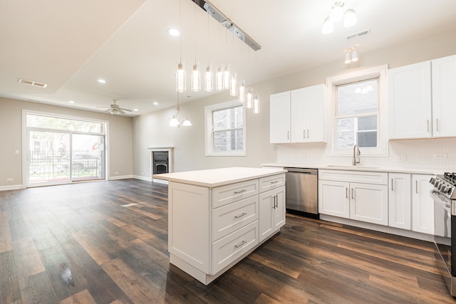 kitchen with appliances with stainless steel finishes, white cabinetry, a kitchen island, and sink